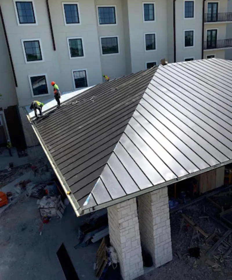 Crew installing standing seam metal roof panels on a commercial project in Trumann